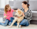 pretty-mother-and-cute-daughter-playing-with-adorable-dog-at-home